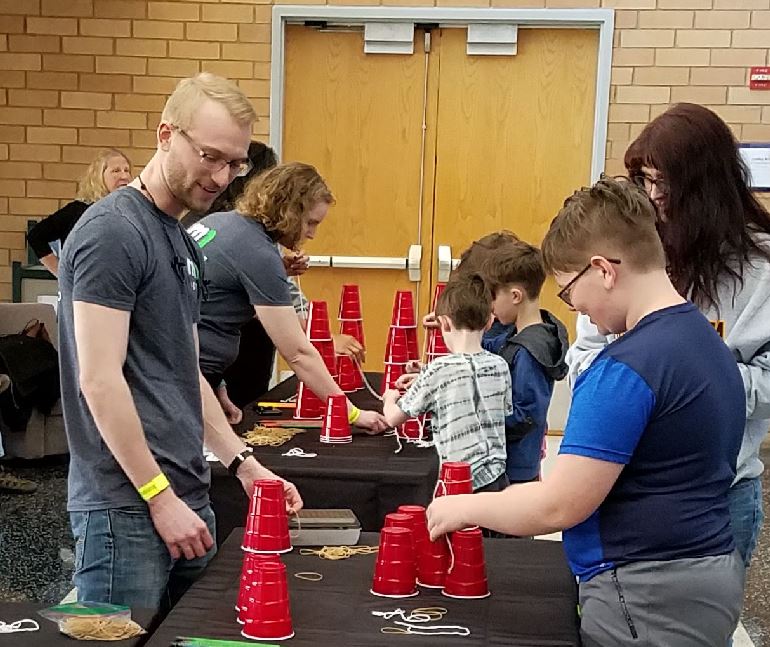 MnDOT employee watches as young person begins to stack red cups.